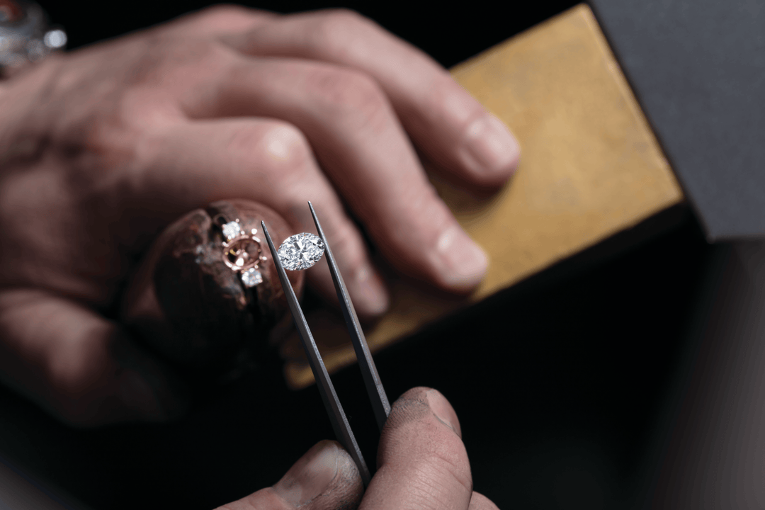 Jeweler holding diamond with tweezers near rose gold engagement ring, showcasing gemstone jewelry craftsmanship