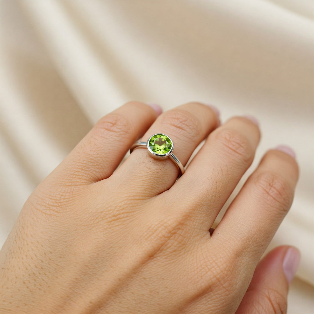 Peridot gemstone ring on finger, silver band, ideal for engagement or everyday wear