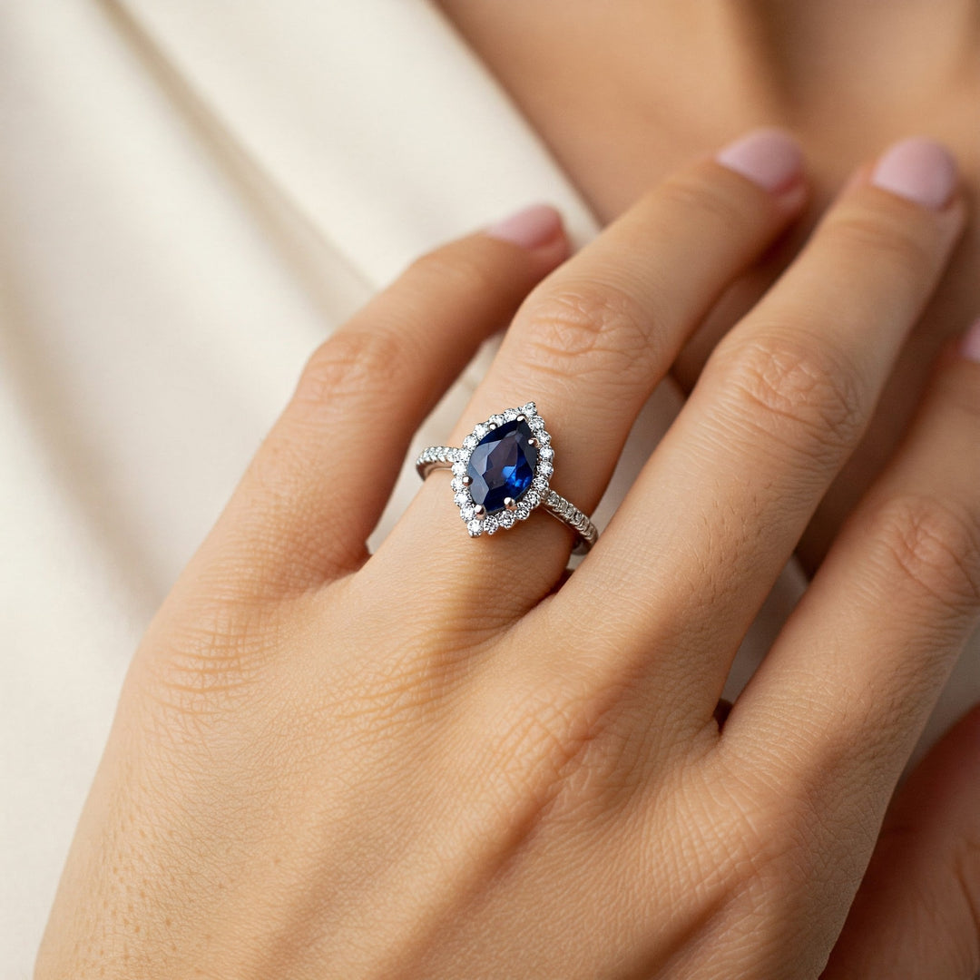Pear-cut sapphire engagement ring with diamond halo and band, elegant gemstone jewelry