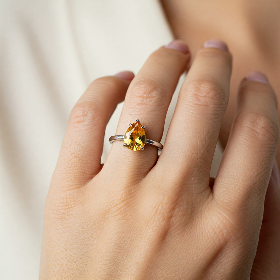 Pear-cut yellow gemstone ring on finger, elegant solitaire design for engagement or fashion jewelry