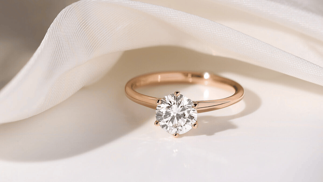 Rose gold solitaire engagement ring with round diamond on white fabric