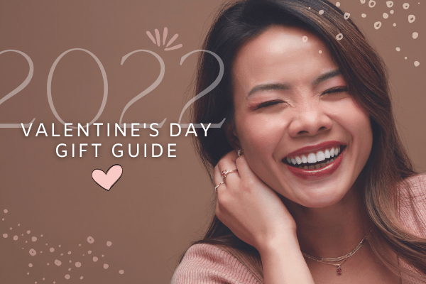 Smiling woman wearing elegant jewelry for Valentine's Day gift guide, featuring rings and necklaces.