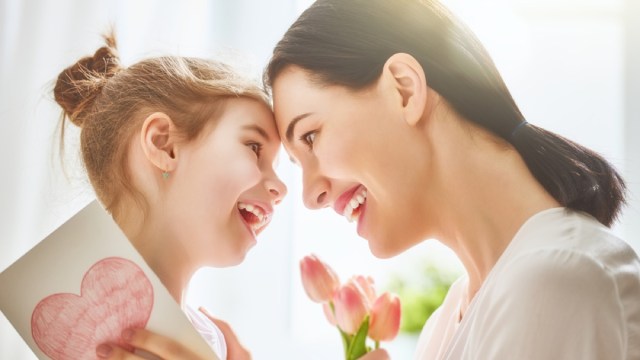 Mother and daughter smiling with pink tulips and heart card, perfect for gifting