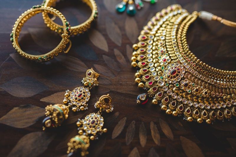 Indian jewelry set with gold necklace, bangles, and earrings featuring gemstones and intricate designs