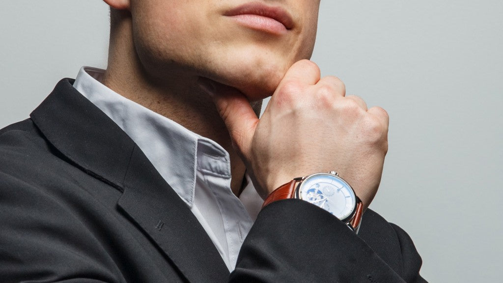 Man in suit wearing luxury watch with brown leather strap, elegant timepiece for formal occasions