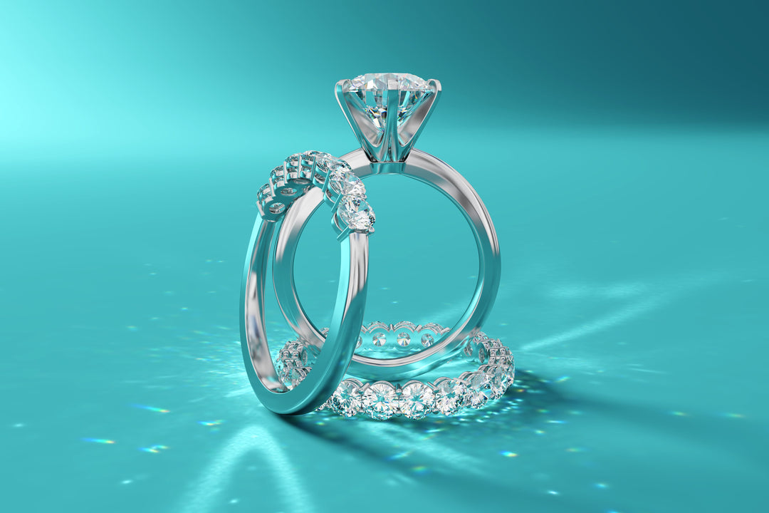 Elegant diamond engagement ring with matching wedding band, sparkling on teal background