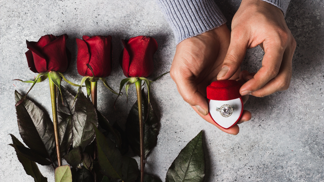 Engagement ring in red box with three red roses, perfect for proposal or wedding